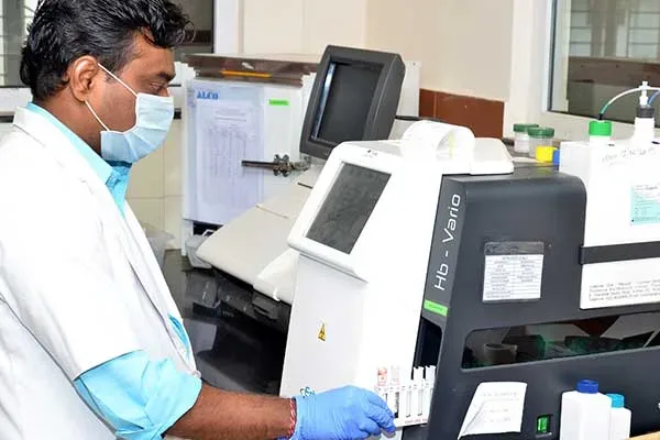 Technician operating a haematology analyser in the clinical laboratory at S S Institute of Medical Sciences, Davangere