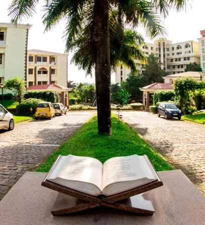 Open Quran monument in a garden courtyard with Yenepoya campus buildings behind at Deralakatte, Mangalore