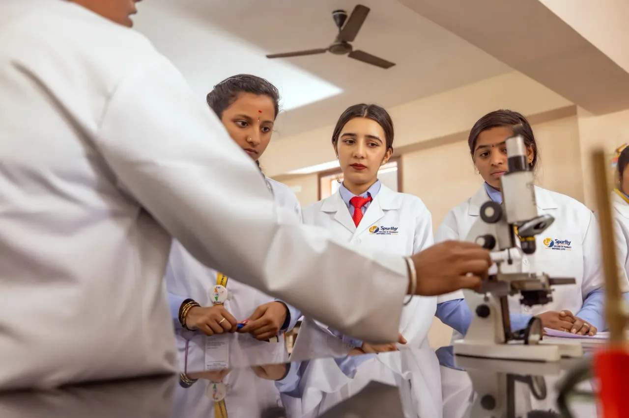 Students in white coats conducting microscope-based laboratory work — Spurthy College of Nursing (Spurthy Institutions)