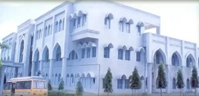 Arched campus block of Al-Ameen Medical College with a college bus in front