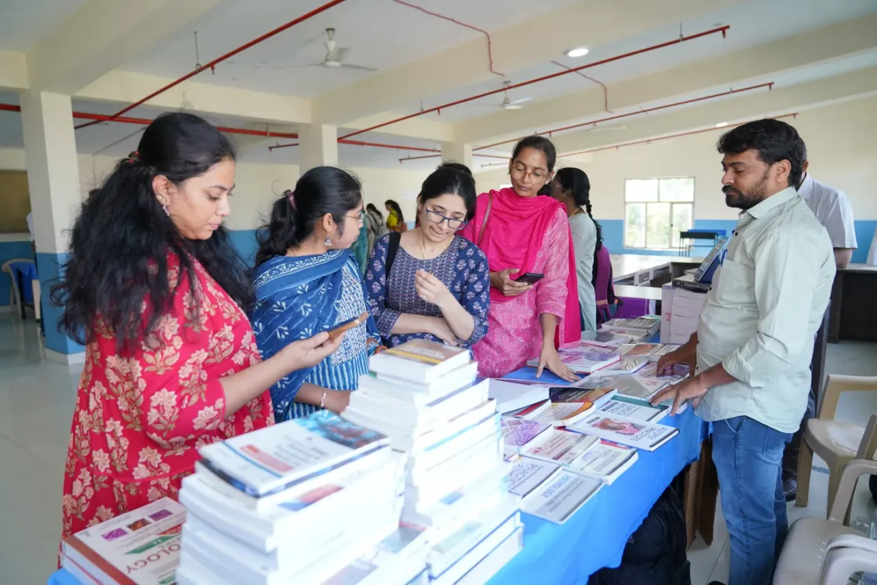 Students browsing medical textbooks at a book exhibition during a CMR Institute of Medical Sciences academic event