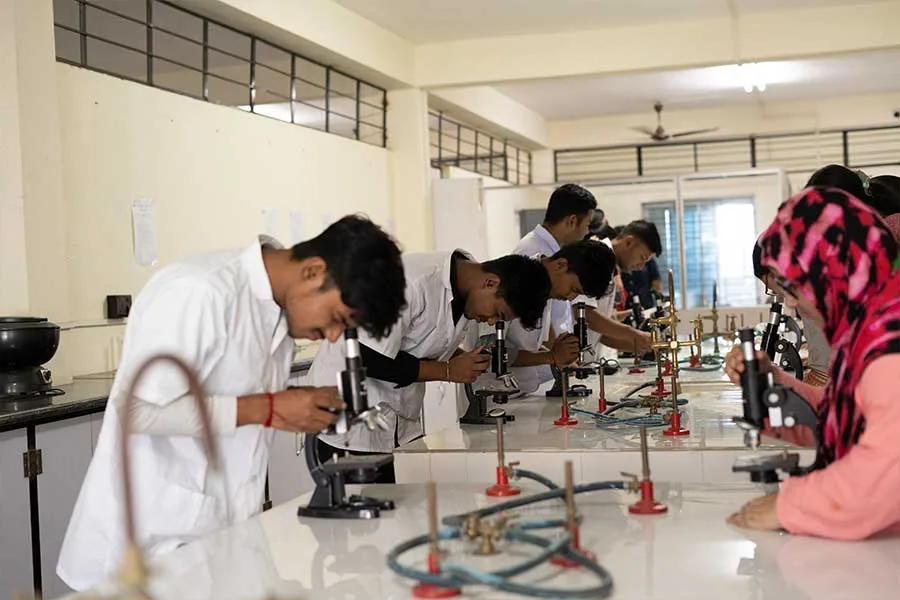 pharmacy-students-looking-through-microscopes-in-science-laboratory — Sahajpath College of Pharmacy