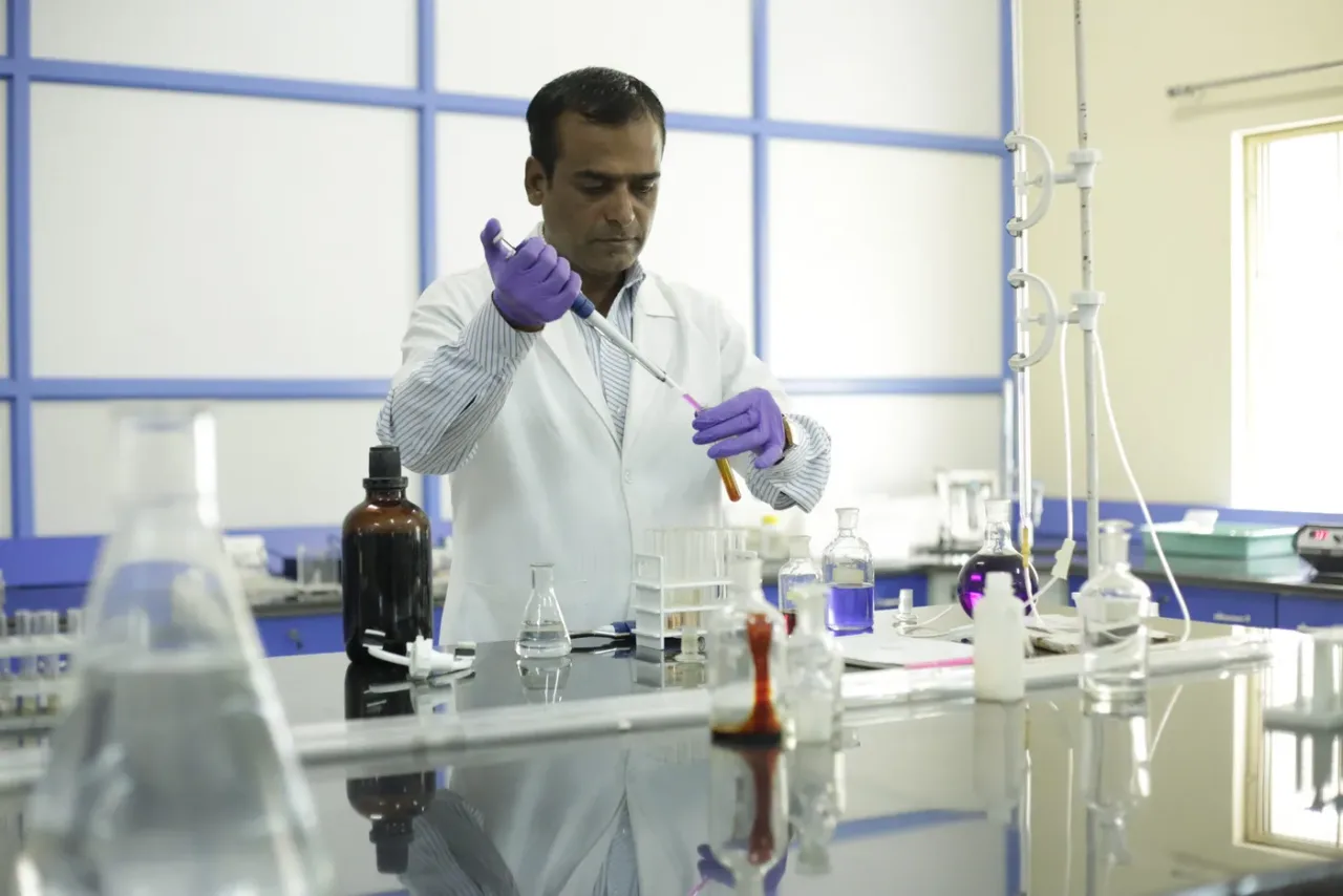 Faculty member pipetting reagents in a biochemistry laboratory at AIMS
