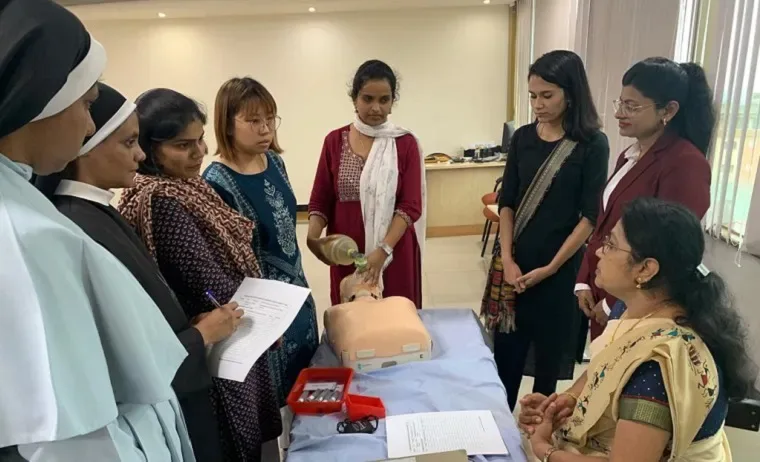 Nursing workshop participants gathered around a patient simulator — Manipal College of Nursing (MCON), Manipal Academy of Higher Education