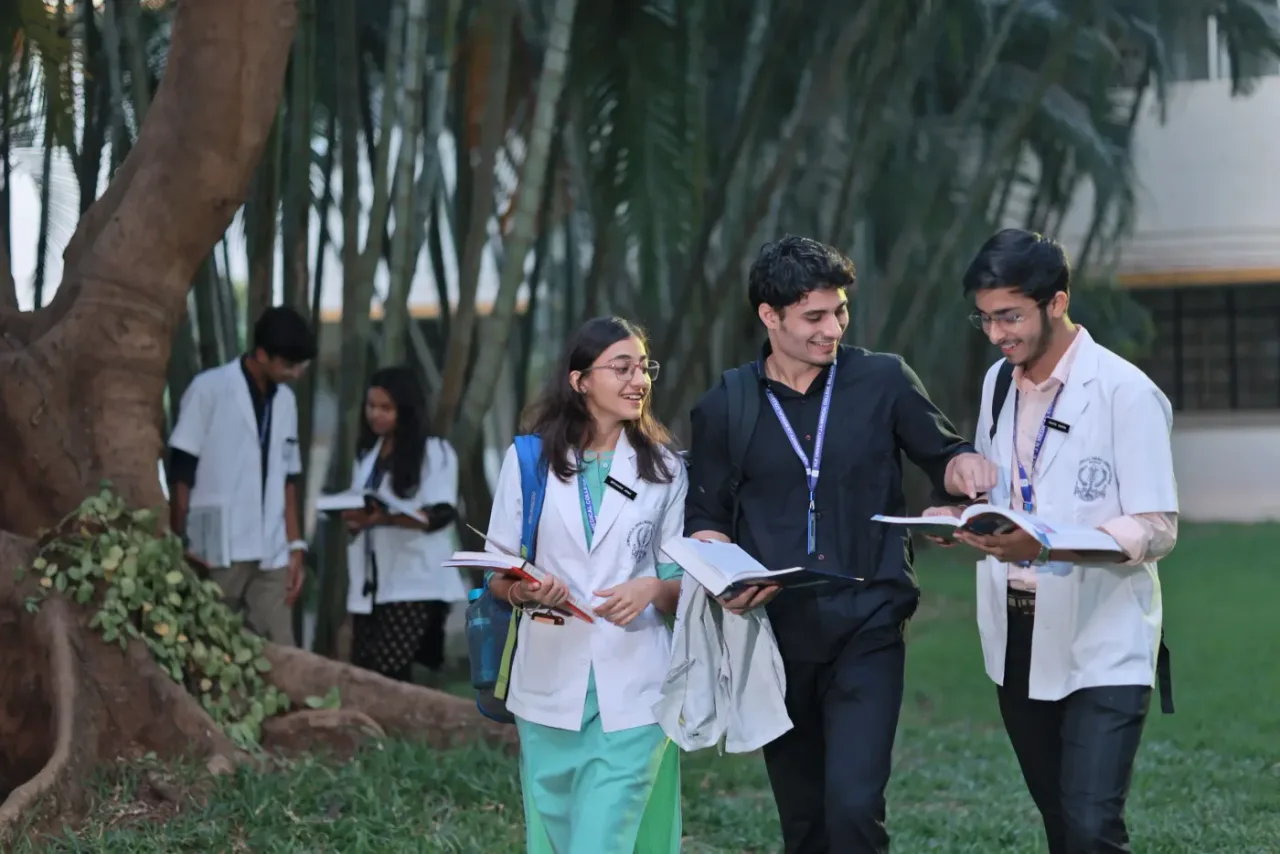 Medical students walking through the tree-lined KAHER JNMC campus in Belagavi