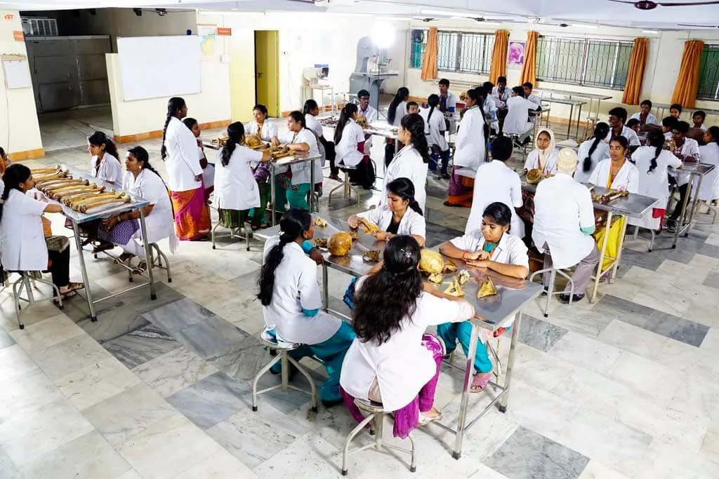 MBBS students in white coats studying bone specimens in the Anatomy osteology hall at ACS Medical College and Hospital, Chennai
