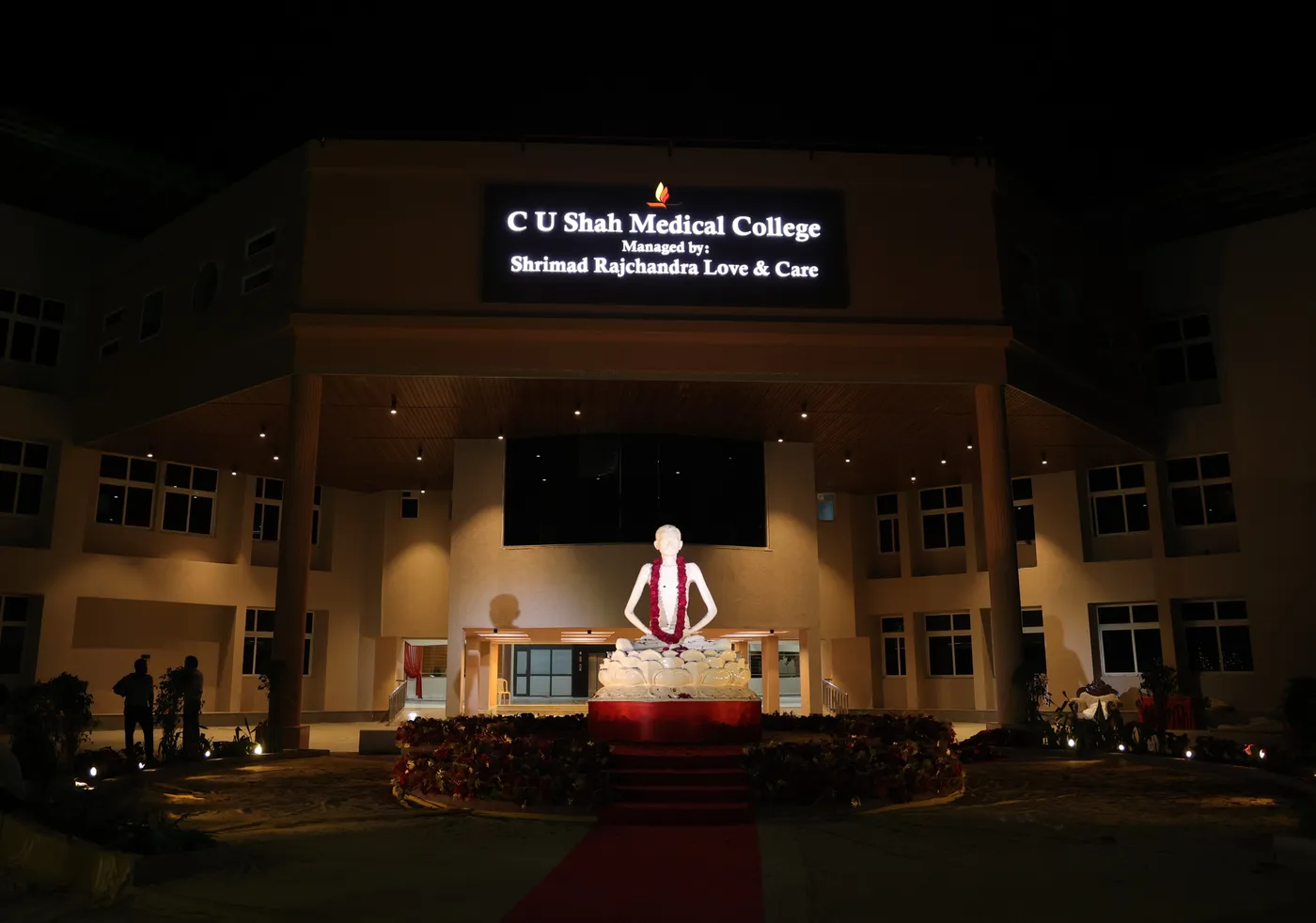 C. U. Shah Medical College main building illuminated at night with the founder's statue lit in the forecourt