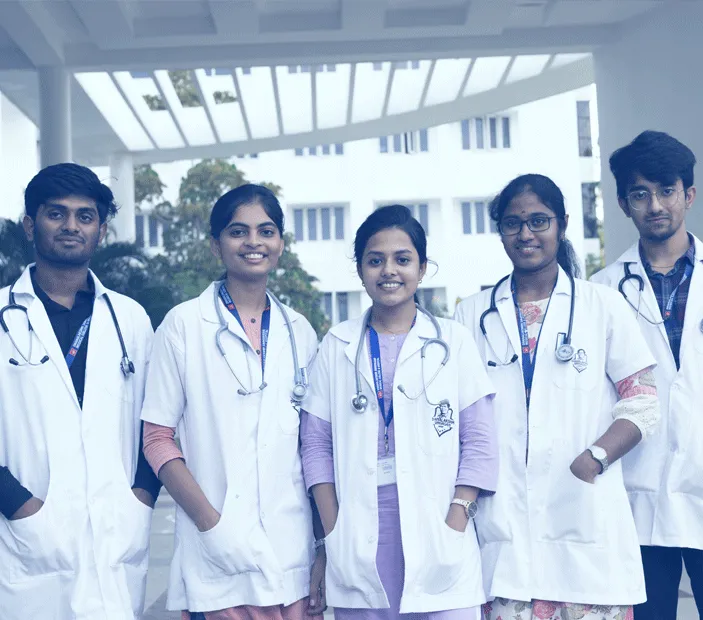 Group of MBBS students in white coats with stethoscopes in front of the college building at Dhanalakshmi Srinivasan Medical College
