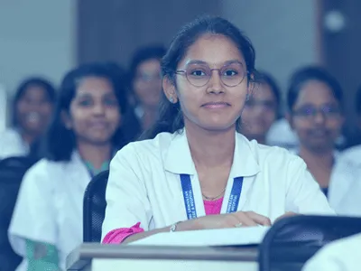 MBBS student in a white coat seated in a classroom at Dhanalakshmi Srinivasan Medical College, Perambalur