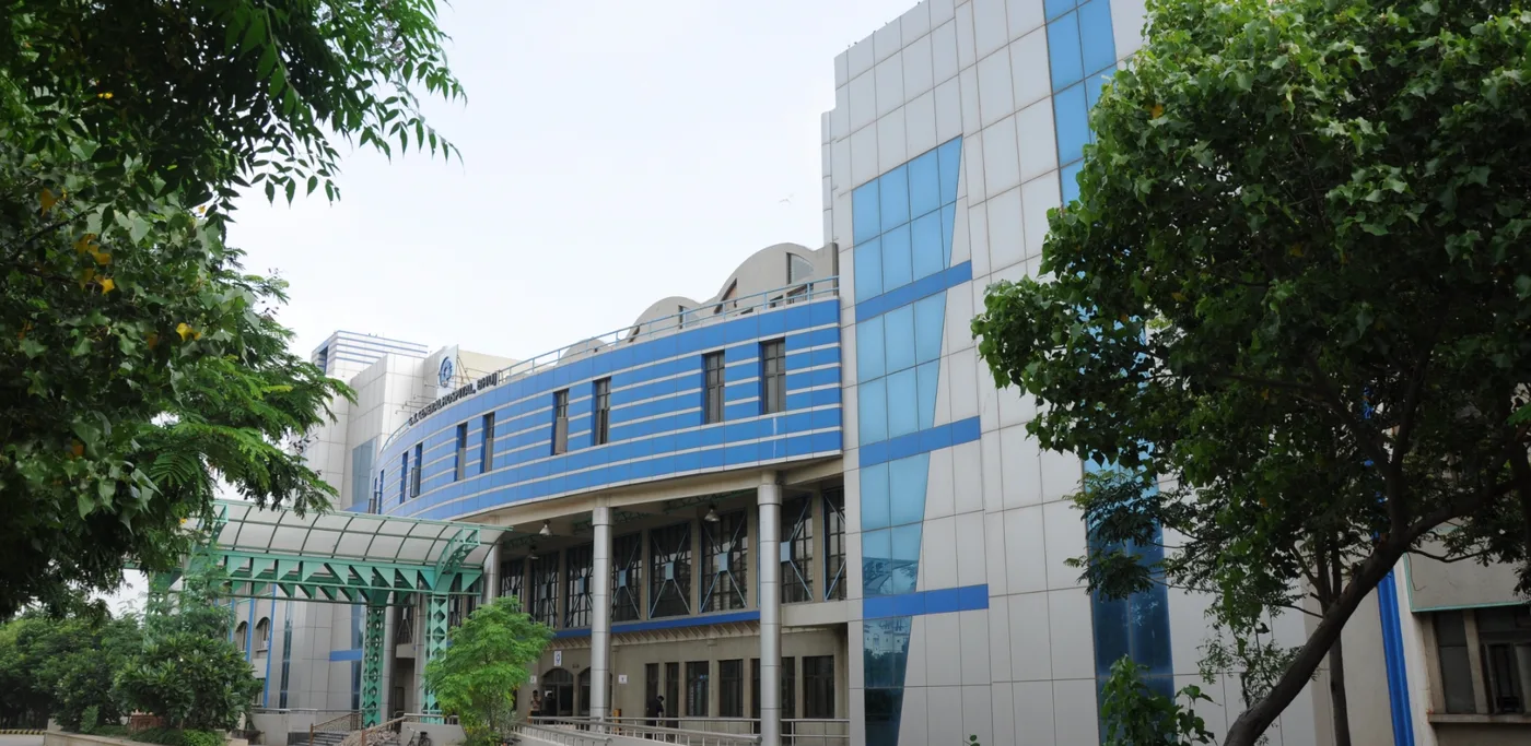 Side view of the G. K. General Hospital teaching block at GAIMS Bhuj, framed by trees