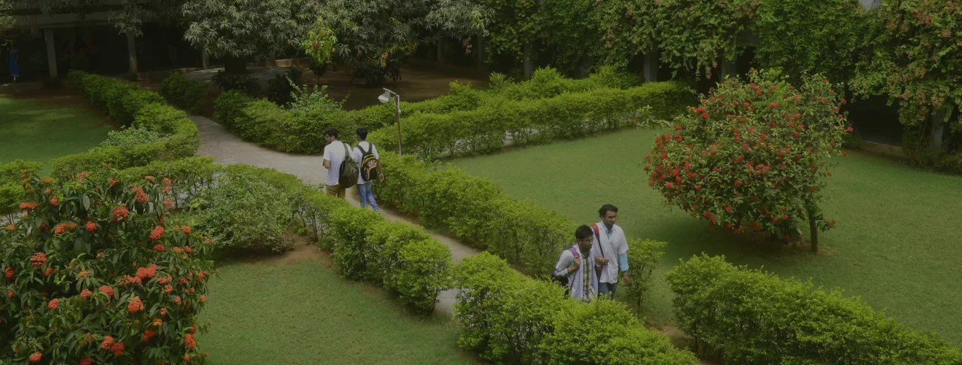 Landscaped green campus grounds of Pramukhswami Medical College, Karamsad, with students walking