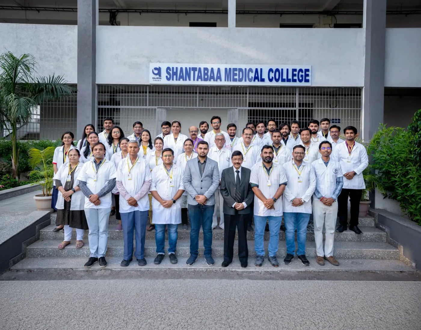 Faculty members of Shantabaa Medical College outside the building under the college name signage, Amreli