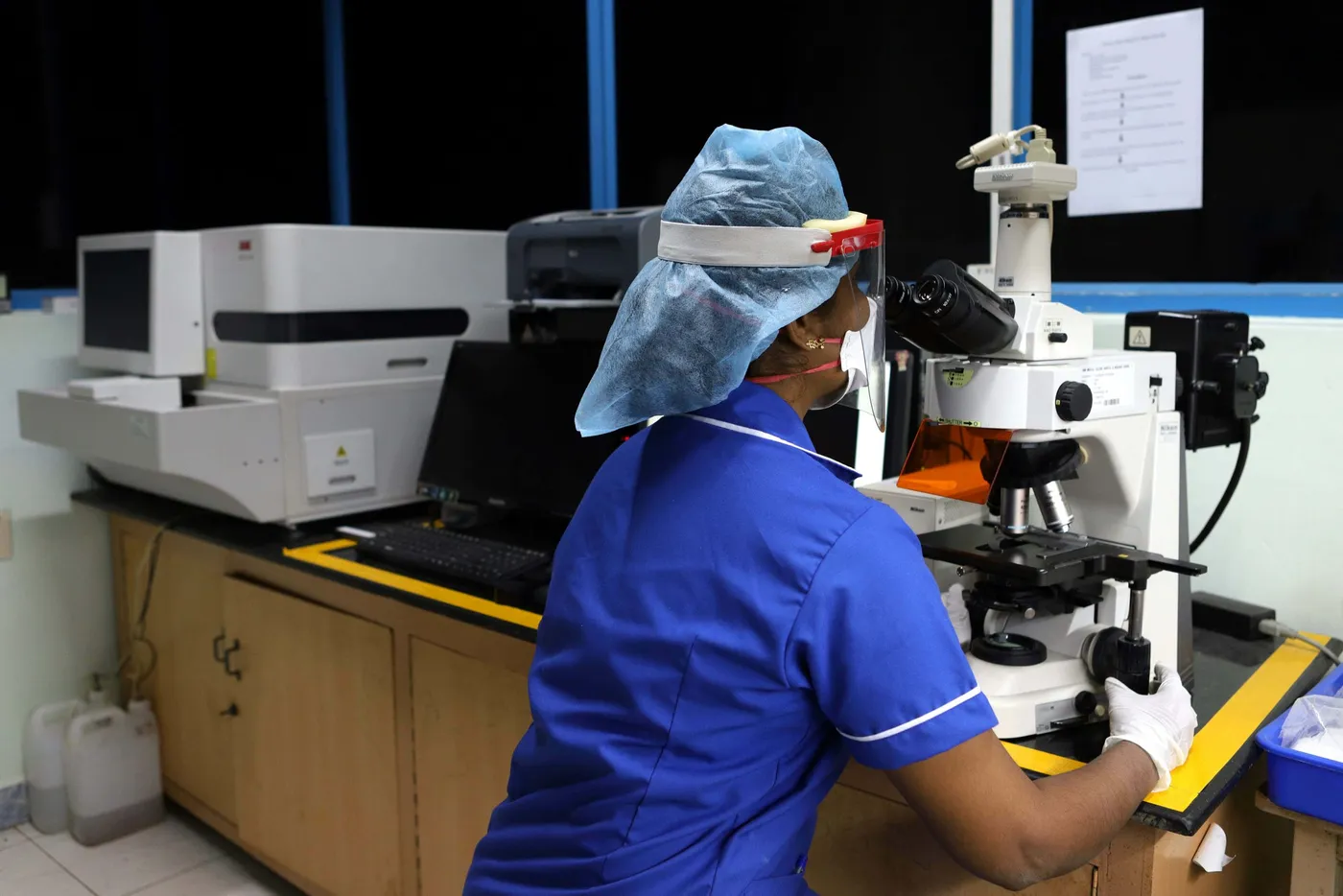 Laboratory technician at a microscope in the central clinical laboratory of SRM Medical College Hospital