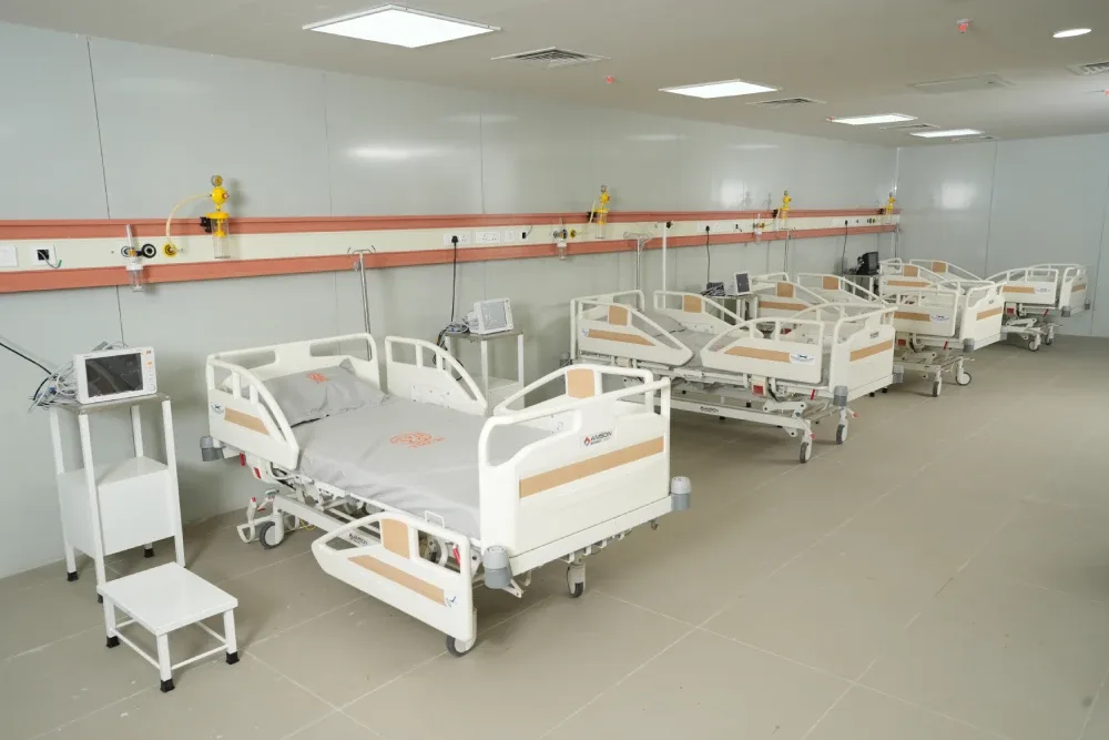 Row of hospital beds with bedside monitors and central oxygen panels in a ward at Takshashila Medical College Hospital