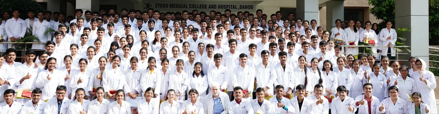 Large group of Zydus Medical College and Hospital students and faculty in white coats outside the college, Dahod
